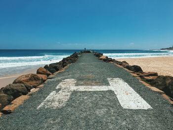 Pier on beach and sea against sky