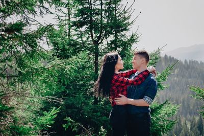 Side view of young couple standing face to face in forest