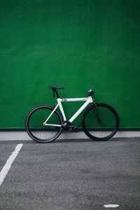 Side view of bicycle parked against wall