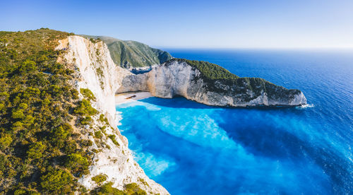 Rock formations by sea against blue sky