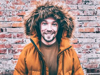 Portrait of smiling young man against brick wall