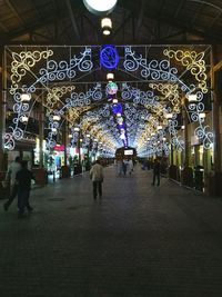 People walking on illuminated street at night