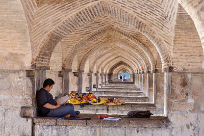 Side view of a man sitting at historical building