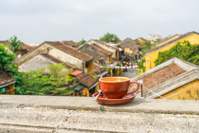 Coffee cup on retaining wall against buildings