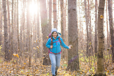 Full length of smiling woman standing in forest