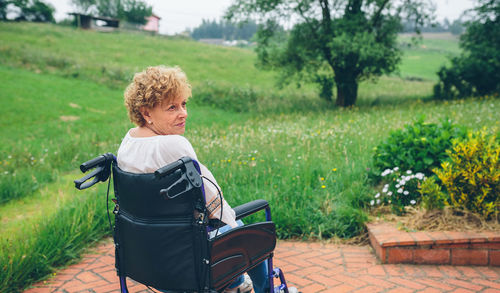 Smiling senior woman sitting on wheelchair at park
