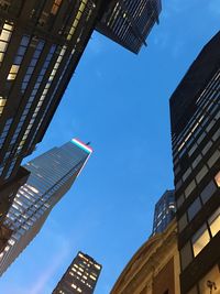 Low angle view of skyscrapers against blue sky