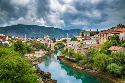 Scenic view of river amidst buildings against cloudy sky