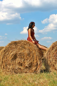 Side view of young woman sitting on field