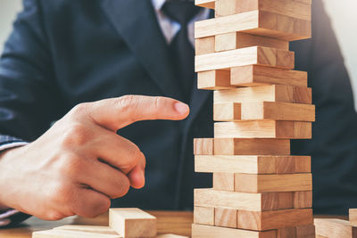 Midsection of businessman gesturing by wooden blocks on table