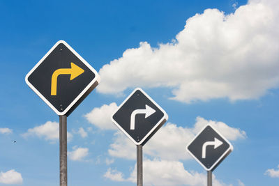Low angle view of road signs against cloudy sky