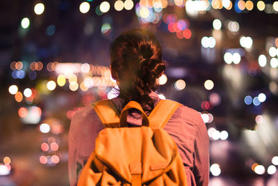 Woman standing by illuminated lighting equipment at night