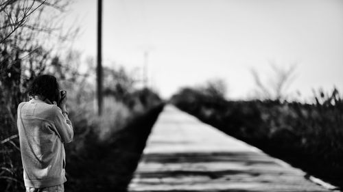 Rear view of man standing on road against sky