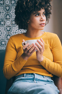 Afro teenage girl having coffee at home