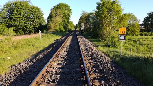 Railroad tracks by trees against clear sky