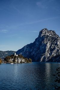 Scenic view of sea and mountains against blue sky