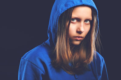 Close-up portrait of young woman against black background