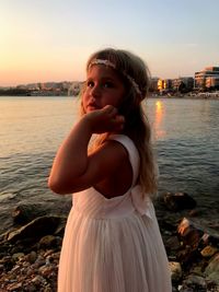 Side view of thoughtful girl standing at beach against sky