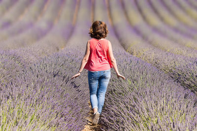 Rear view of woman on street amidst field