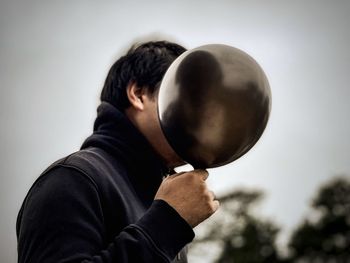 Portrait of man holding balloons against white background