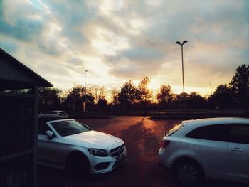 Cars on street in city against sky during sunset