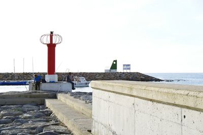 Man by retaining wall against clear sky