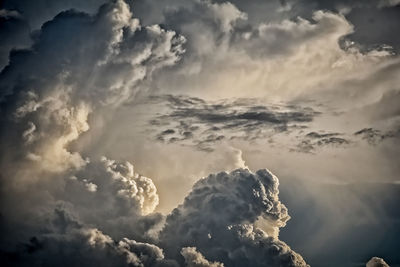 Low angle view of sunlight streaming through clouds