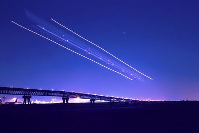 Low angle view of illuminated airplane against clear blue sky