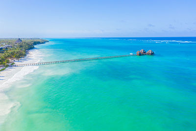 Aerial shot of the stilt hut with palm thatch roof washed with turquoise indian ocean waves on 
