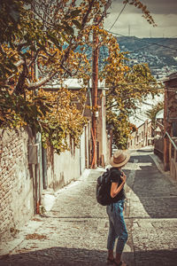 Rear view of woman walking on sidewalk in city