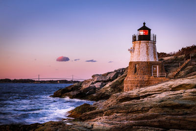 Lighthouse amidst sea and buildings against sky