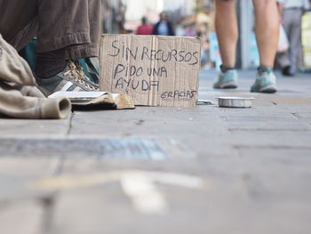 Low section of beggar with sign board on street