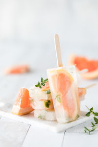 A grapefruit thyme popsicle leaning against a stack of the same popsicles.