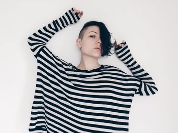 Portrait of young woman standing against white background
