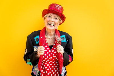 Cheerful senior woman standing against yellow wall