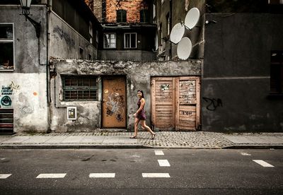 Woman walking on footpath by old building