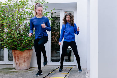 Full length of women standing against blue wall