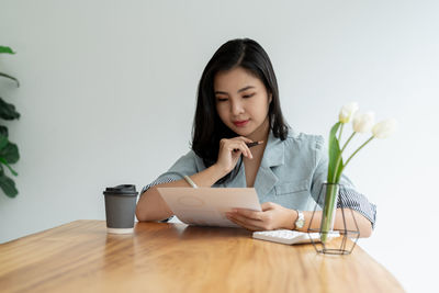 Portrait of young woman using mobile phone while sitting on table