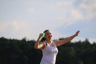 Cheerful woman holding string against sky