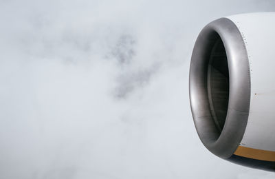 Cropped jet engine against cloudy sky