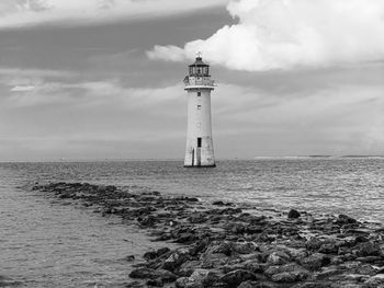 Lighthouse by sea against sky