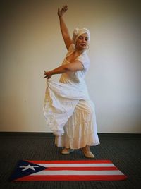 Full length of female dancer by puerto rican flag against wall