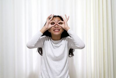 Portrait of beautiful young woman standing against wall