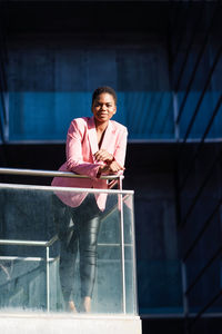 Portrait of a smiling young woman standing against railing