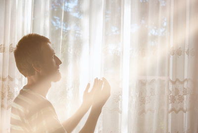 Side view of young woman looking through window