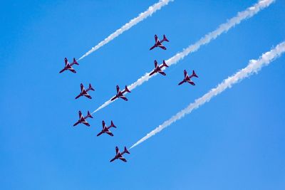 Low angle view of airshow against clear blue sky