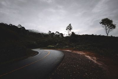 Road amidst trees against sky