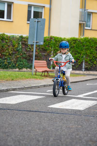 Rear view of man riding push scooter on road