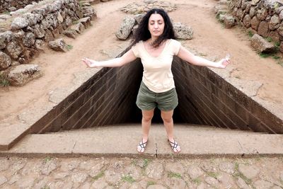 Full length portrait of woman standing against wall