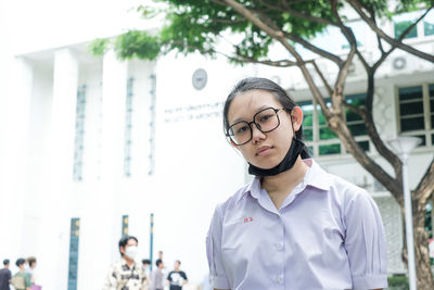 Portrait of young woman standing against building